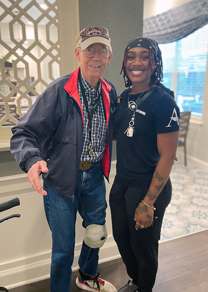 A team member and senior man smile for a photo together at the Rushwood Senior Living.