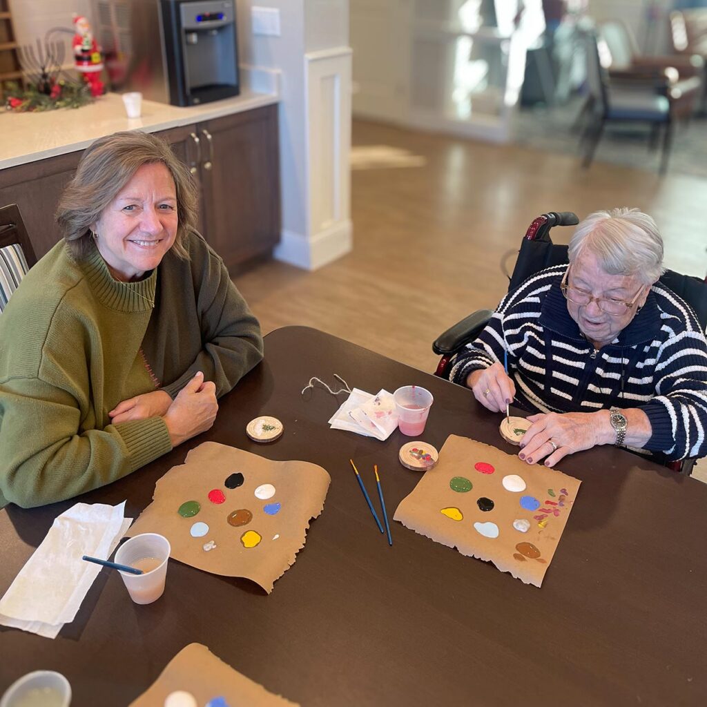 A resident and loved one smile during a relaxed art session at The Rushwood Senior Living.