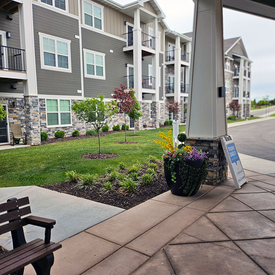 The exterior of The Rushwood showcases freshly planted mulch beds, trees, and planters.
